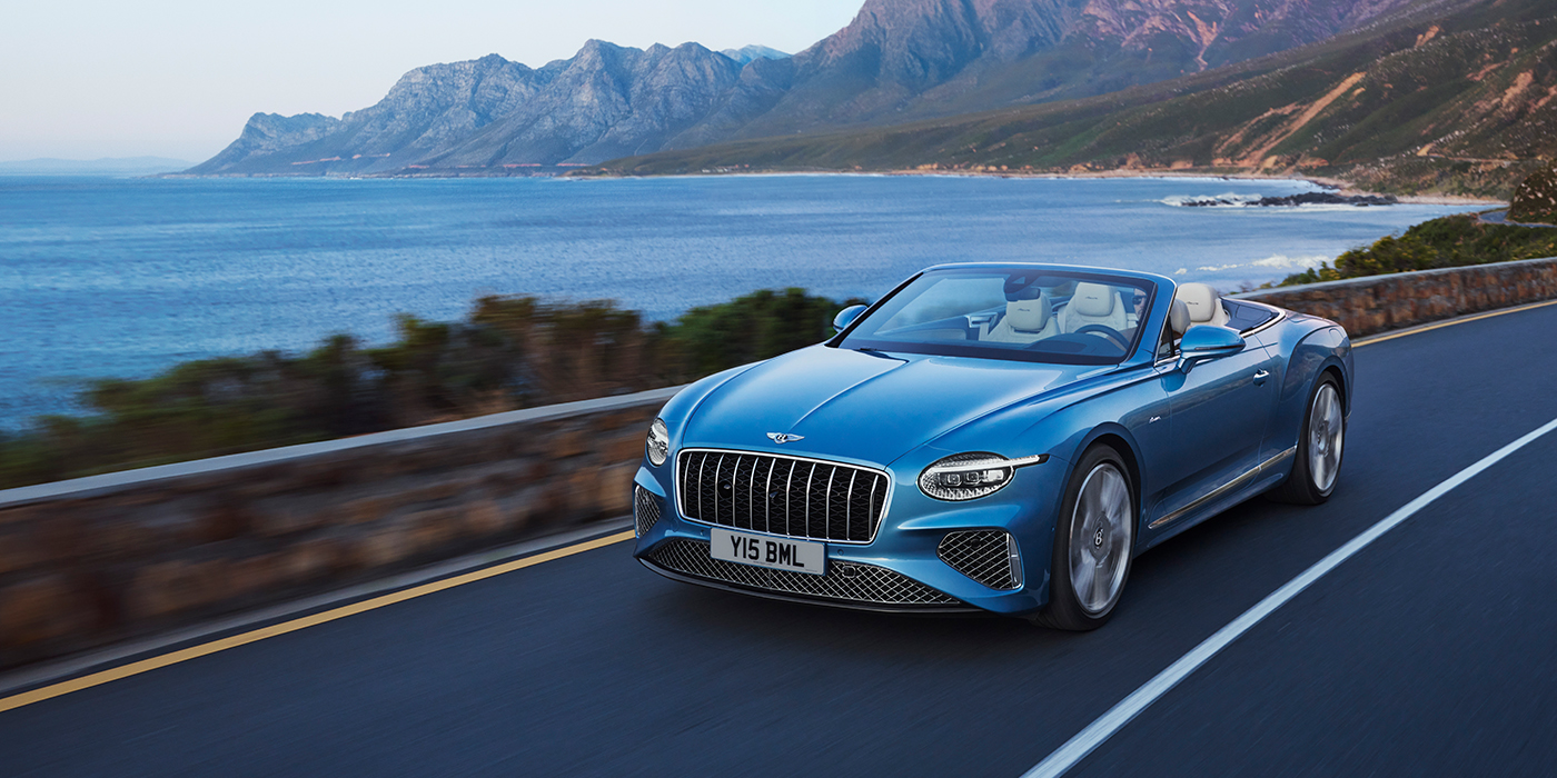 Bach Premium Cars GmbH | Bentley Mannheim New Bentley Continental GTC Azure convertible in Light Windsor blue paint with 22 inch Azure wheels and chrome grill, driving dynamically by the sea