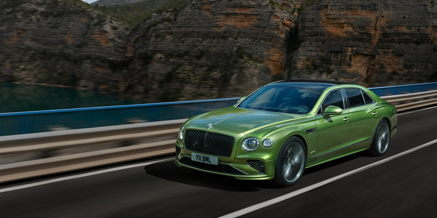 Bach Premium Cars GmbH | Bentley Mannheim Bentley New Flying Spur Speed v8 hybrid sedan driving dynamically on a mountain road in Tourmaline Green paint
