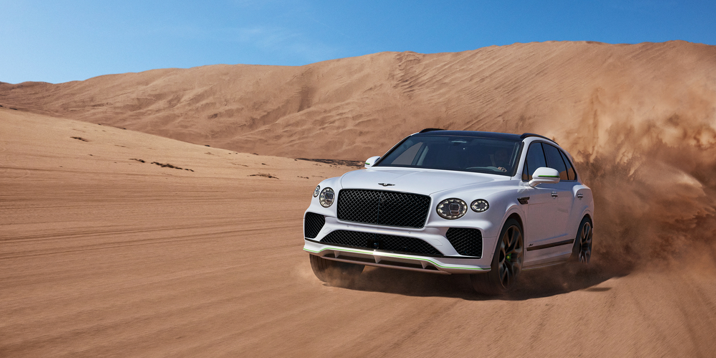 Bach Premium Cars GmbH | Bentley Mannheim Bentley Bentayga Speed SUV front three quarter in Snow Quarts Pearlescent by Mulliner white paint driving dynamically through the desert
