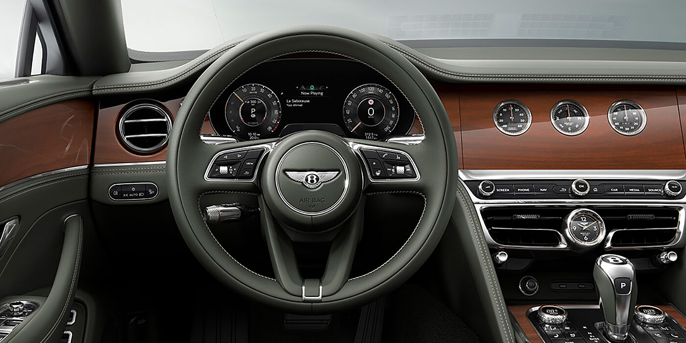 Bach Premium Cars GmbH | Bentley Mannheim New Bentley Flying Spur sedan front cabin in Cumbrian Green hide and Crown Cut walnut veneer showing steering wheel and Rotating Display with three clocks on face