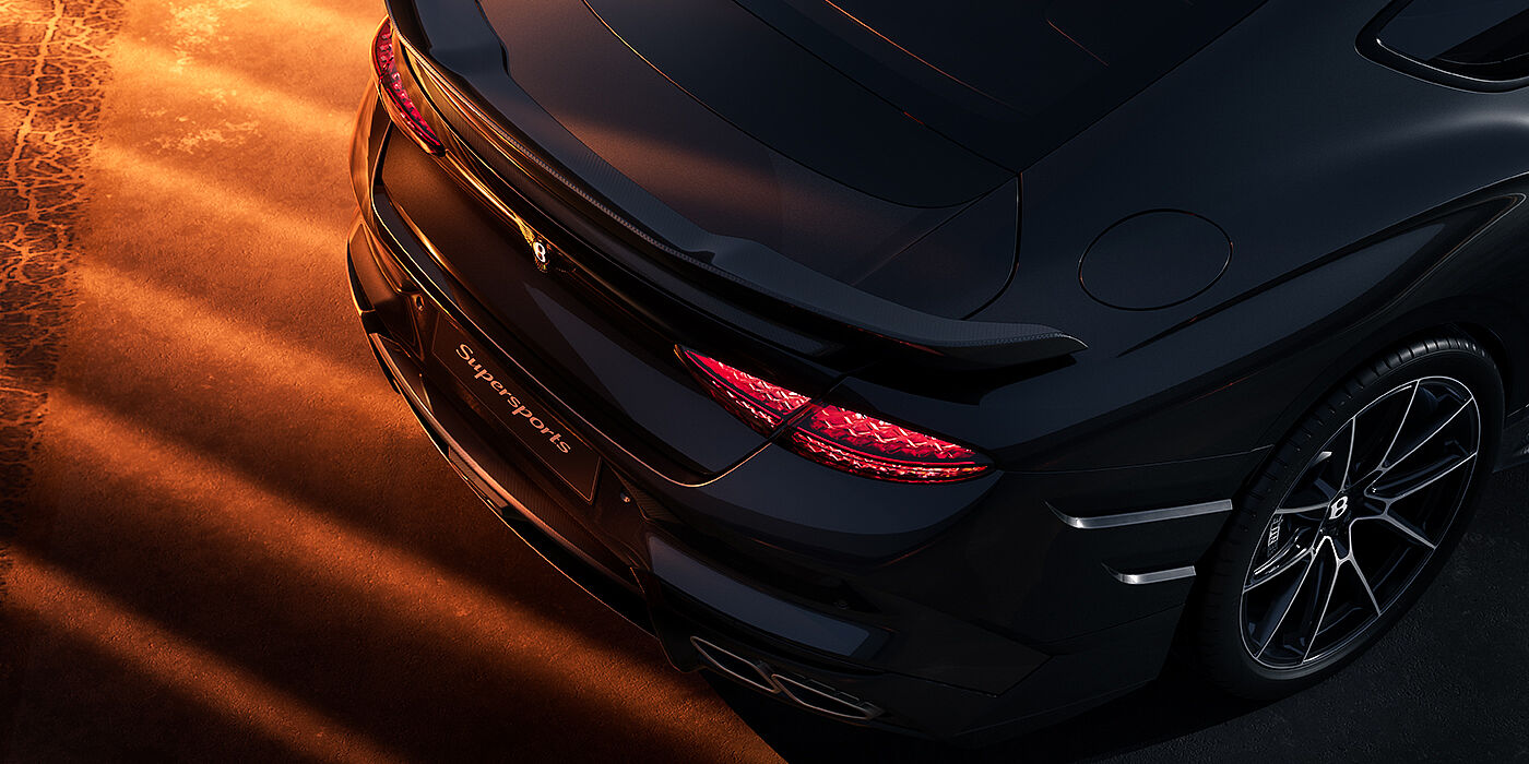 Bach Premium Cars GmbH | Bentley Mannheim Bentley Supersports rear overhead view showing illuminated rear lamps and Supersports Forged Alloy wheel in Anthracite paint against a dark grey and red background